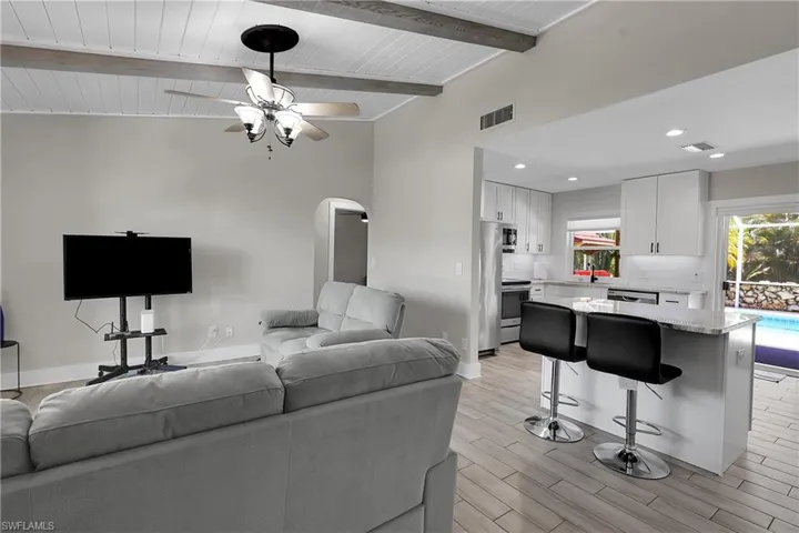 Living area with arched walkways, a ceiling fan, wood finish floors, recessed lighting, and a wood ceiling with exposed beams