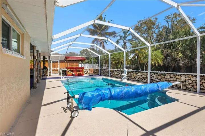 View of swimming pool with patio surround, a lanai, a sunroom, a fenced backyard, and a covered pool