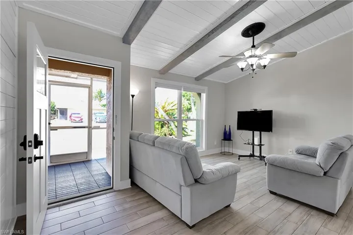 Living room featuring wood tiled floors, vaulted ceiling with beams, and ceiling fan