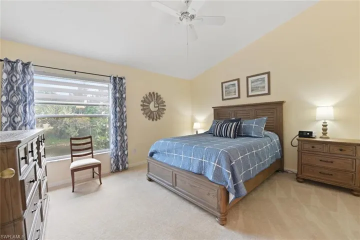 Carpeted bedroom with ceiling fan and lofted ceiling