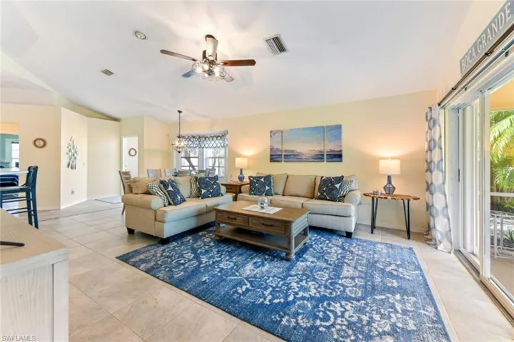 Tiled living room with a wealth of natural light and ceiling fan with notable chandelier