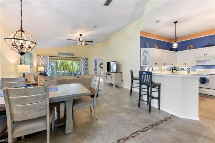 Dining space with ceiling fan with notable chandelier, vaulted ceiling, and light tile floors