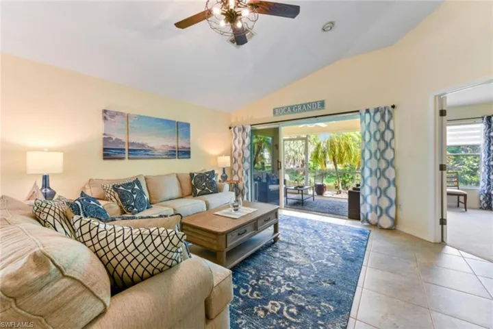Living room with tile floors, ceiling fan, and lofted ceiling