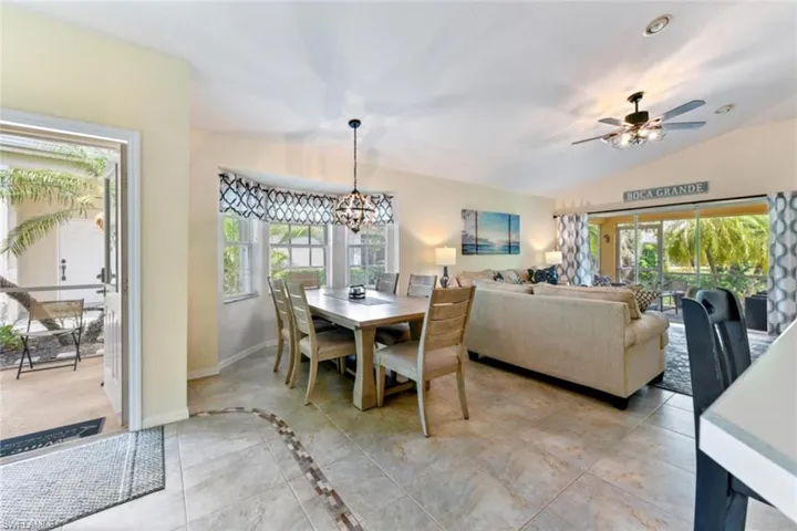 Tiled dining room featuring a wealth of natural light, lofted ceiling, and ceiling fan with notable chandelier