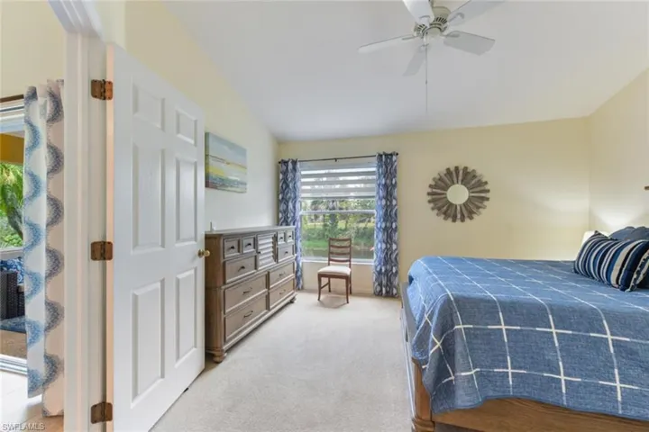 Carpeted bedroom with ceiling fan and lofted ceiling