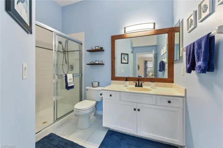 Bathroom with tile flooring, vanity, toilet, and a shower with door