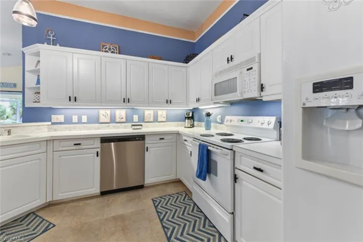 Kitchen with white appliances, white cabinets, and light tile floors