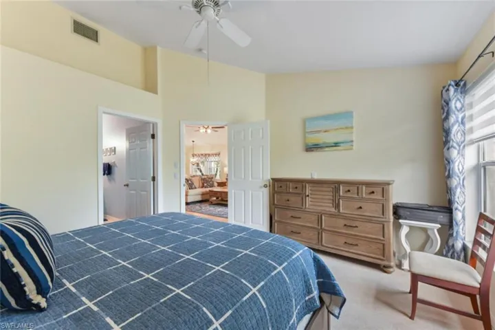 Carpeted bedroom with ensuite bathroom, ceiling fan, and lofted ceiling