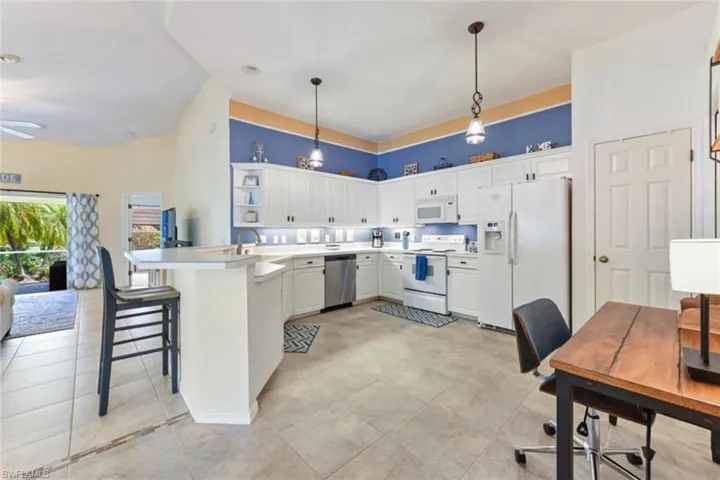 Kitchen with kitchen peninsula, a kitchen breakfast bar, hanging light fixtures, white appliances, and light tile floors