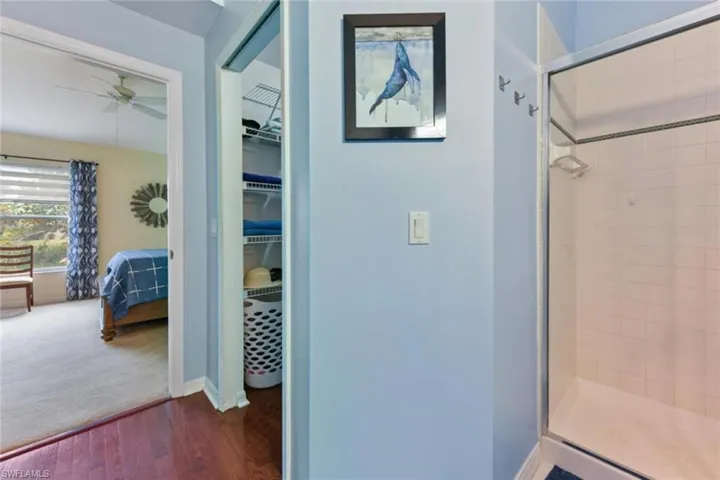 Bathroom featuring ceiling fan, an enclosed shower, and hardwood / wood-style flooring