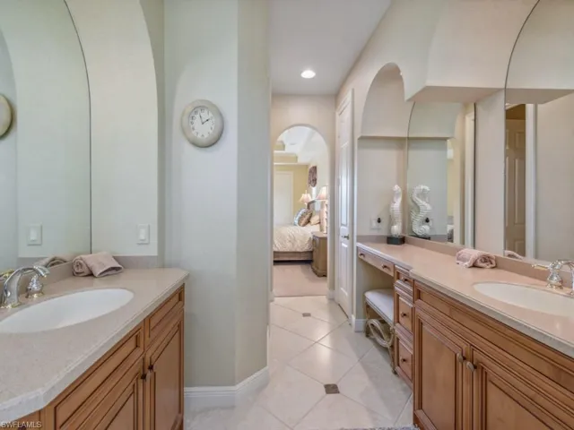 Bathroom featuring tile patterned floors, a sink, connected bathroom, and two vanities