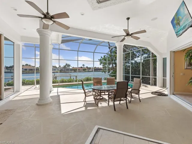 View of patio / terrace with a water view, ceiling fan, an outdoor pool, and a lanai