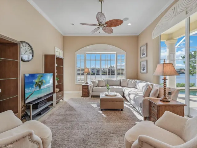 Living room featuring a ceiling fan, ornamental molding, and a healthy amount of sunlight