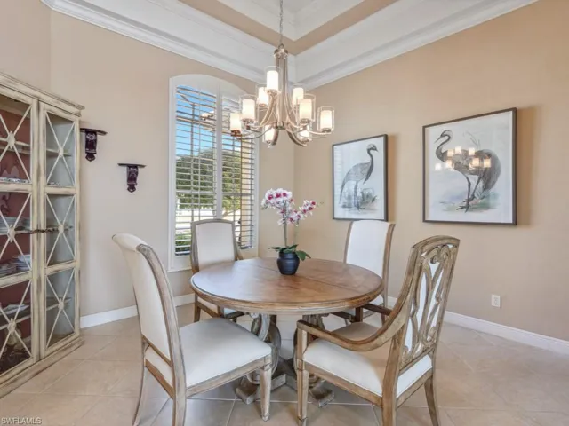 Dining room with crown molding, light tile patterned floors, baseboards, and an inviting chandelier