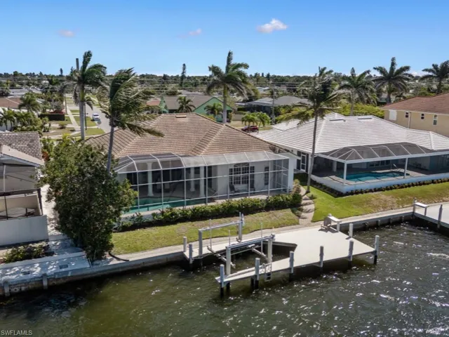 View of dock with a water view, boat lift, an outdoor pool, a residential view, and a lanai