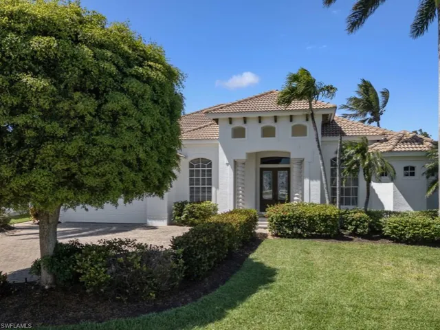 Mediterranean / spanish home with a tiled roof, a garage, stucco siding, a front lawn, and driveway