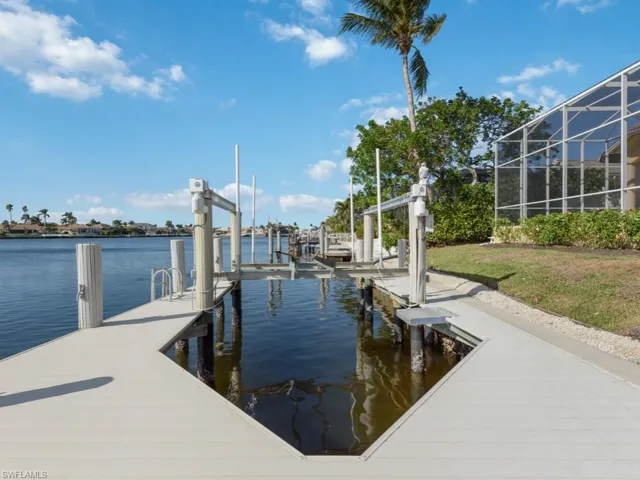 View of dock with a lanai, boat lift, and a water view