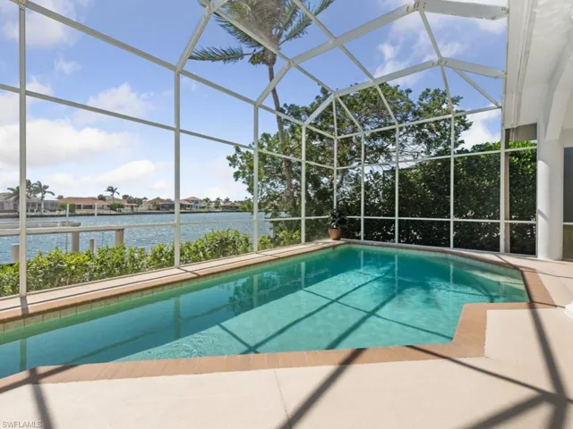 Pool with a water view, a patio area, and glass enclosure