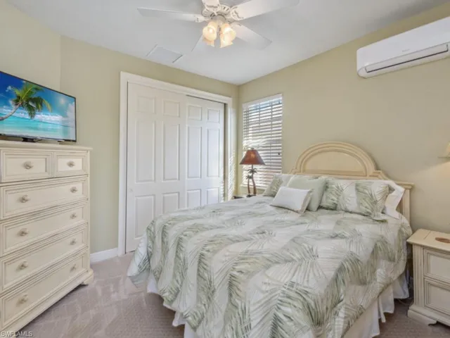 Bedroom with a closet, baseboards, an AC wall unit, a ceiling fan, and light colored carpet
