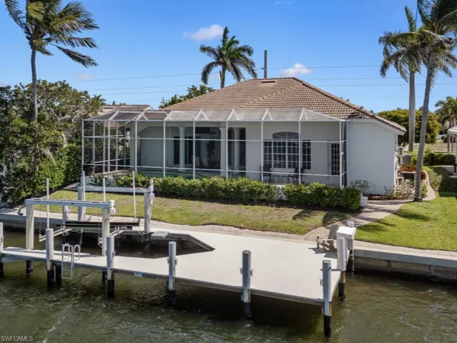 View of dock featuring boat lift, a lawn, glass enclosure, and a water view