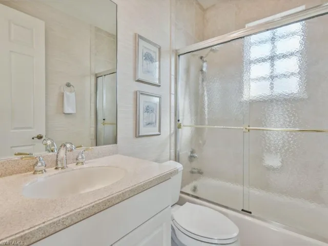 Bathroom with toilet, shower / bath combination with glass door, and vanity