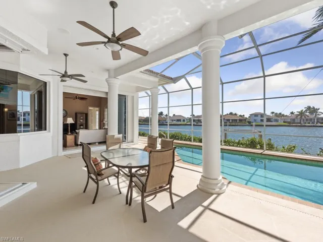 Outdoor pool with a patio area, glass enclosure, a water view, and a ceiling fan