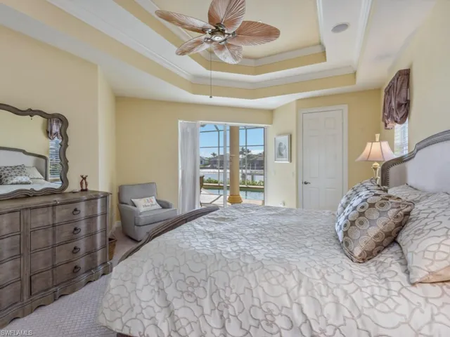 Bedroom with a water view, crown molding, a tray ceiling, access to exterior, and carpet flooring