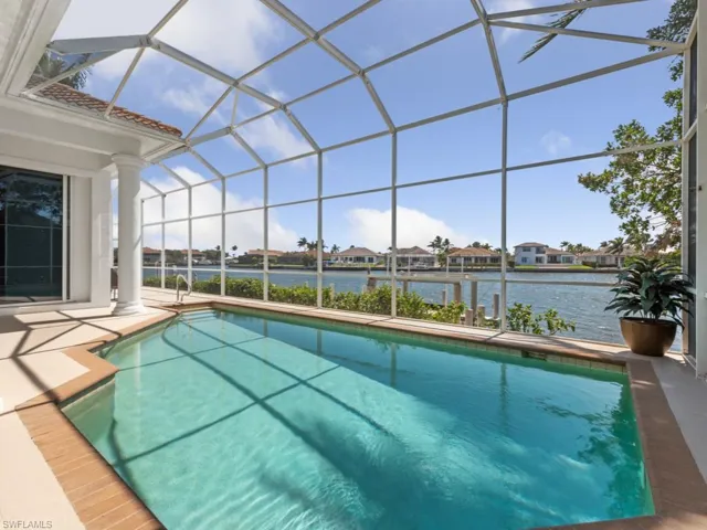 Outdoor pool with a patio area, glass enclosure, and a water view