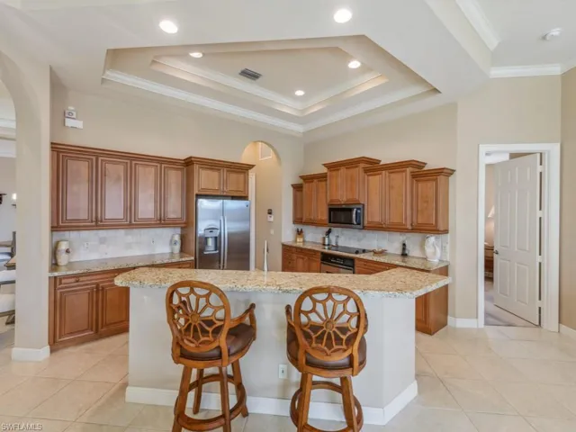 Kitchen with light tile patterned floors, visible vents, brown cabinetry, stainless steel appliances, and arched walkways