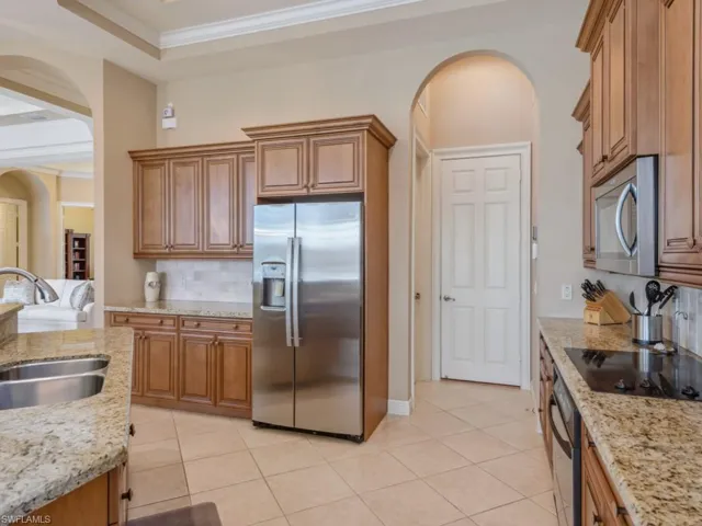 Kitchen featuring a sink, brown cabinetry, arched walkways, and stainless steel appliances