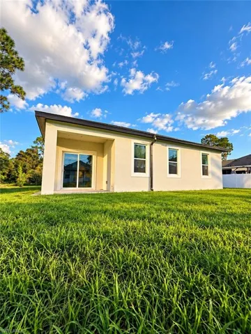 Stucco exterior featuring a covered patio, sliding glass door, and vinyl-framed windows