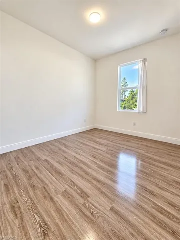 Neutral-toned interior space featuring wood-finish flooring and a single-pane window