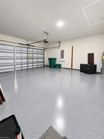 Attached garage featuring an epoxy-coated floor, automatic overhead door opener, recessed lighting, and ceiling attic access