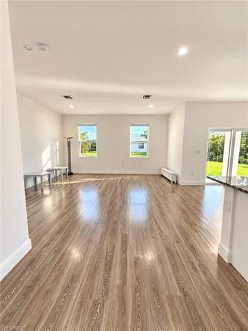 Open-concept interior featuring wood-finish flooring, recessed lighting, and multiple windows