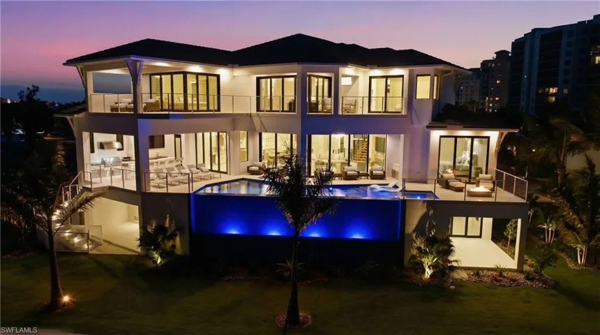 Rear view of house with an infinity pool, a balcony, a yard, and an outdoor lounge area - Virtually Edited Image