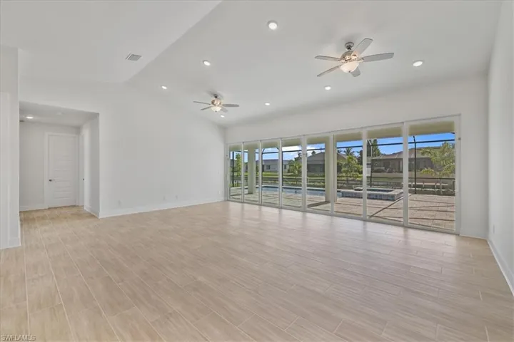 Unfurnished room with recessed lighting, lofted ceiling, wood finish floors, and ceiling fan
