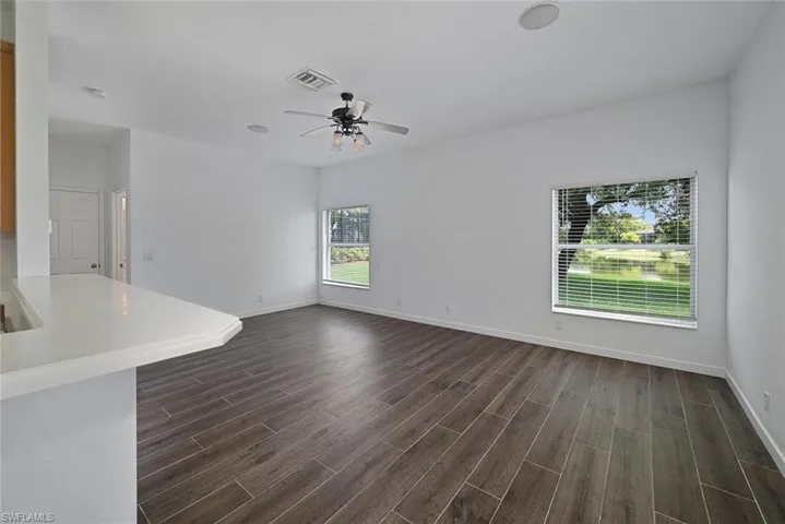 Unfurnished living room featuring ceiling fan and dark hardwood / wood-style floors