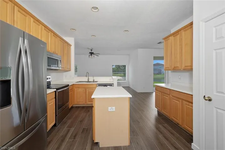 Kitchen featuring stainless steel appliances, sink, kitchen peninsula, a kitchen island, and dark wood-type flooring