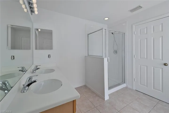 Bathroom featuring an enclosed shower, tile patterned floors, and double sink vanity
