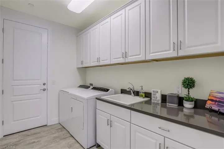 Washroom featuring cabinet space, independent washer and dryer, and light wood-style flooring