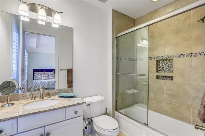 Ensuite bathroom featuring vanity and shower / bath combination with glass door