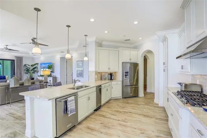 Kitchen featuring arched walkways, a peninsula, ornamental molding, appliances with stainless steel finishes, and a ceiling fan