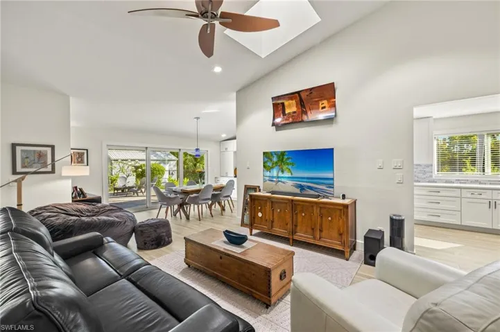 Living area featuring a skylight, tons of natural light, ceiling fan, luxury vinyl flooring, and high vaulted ceiling.