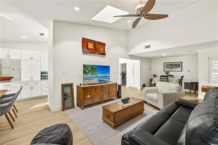 Living area with a ceiling fan, high vaulted ceiling, luxury vinyl flooring, recessed lighting, and a skylight