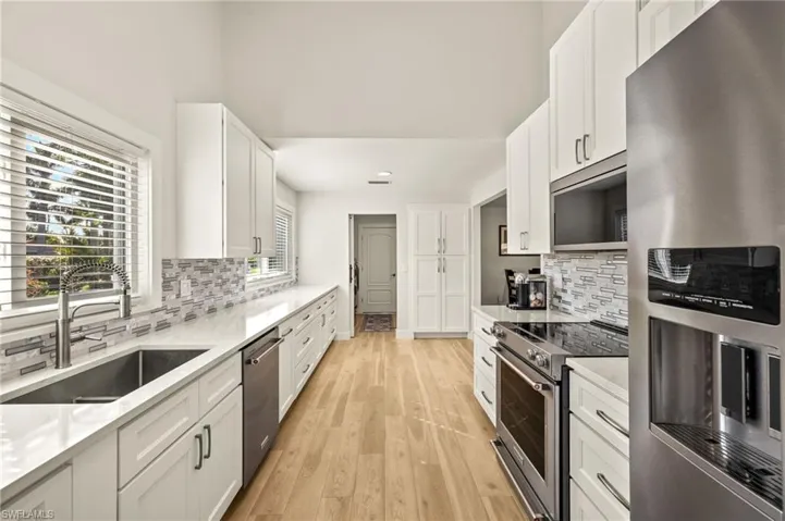 Kitchen with stainless steel appliances, light countertops, white cabinets, and recessed lighting