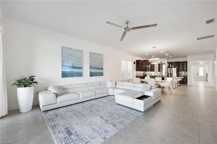 Living area with ceiling fan, ornamental molding, light tile patterned flooring, and visible vents