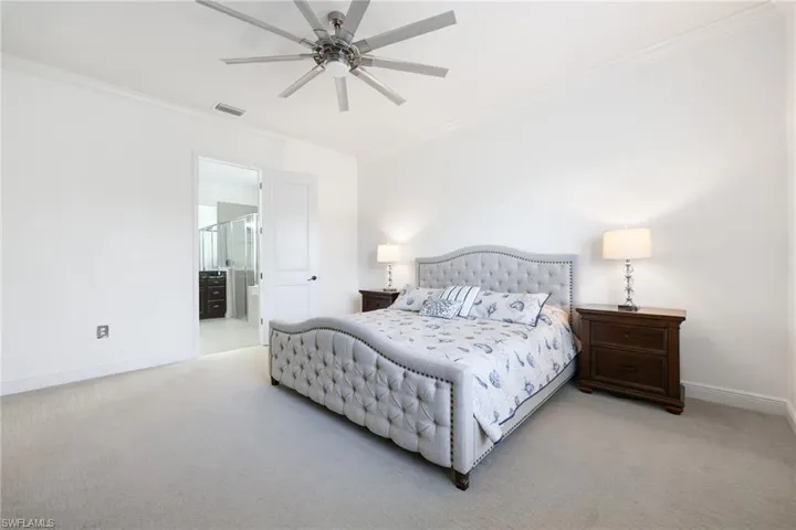Bedroom featuring light carpet, baseboards, visible vents, and ornamental molding