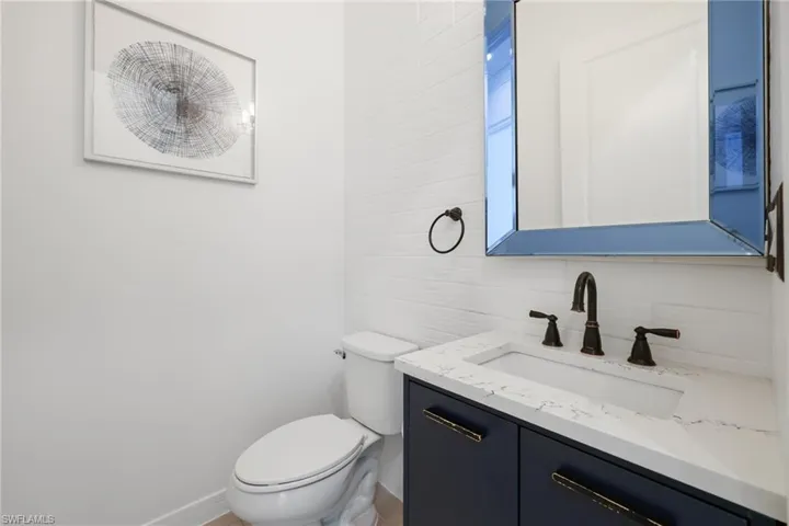Half bath featuring tasteful backsplash, baseboards, vanity, and toilet