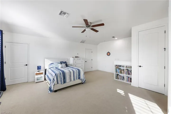 Bedroom with baseboards, visible vents, and light colored carpet