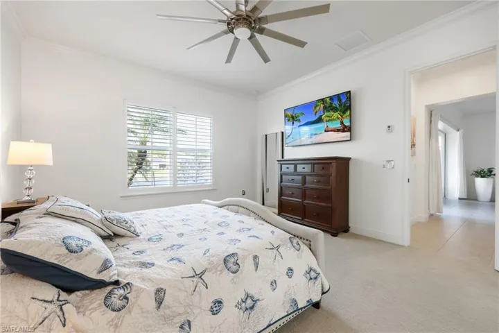 Bedroom featuring a ceiling fan, light colored carpet, crown molding, and baseboards
